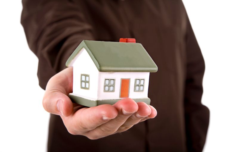 Person holding small house in their palm